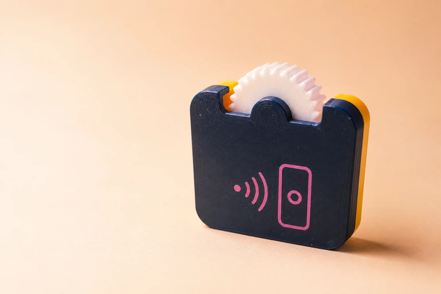 Working MakeJoy NFC Pocket Fidget prototype with a navy printed body, white wheel, and pink NFC symbol