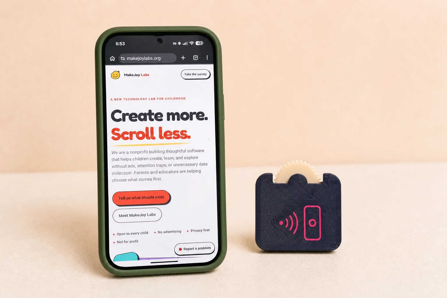 A phone displaying the MakeJoy Labs website next to the assembled NFC Pocket Fidget